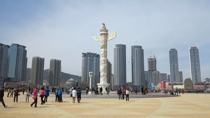 Monument column in Xinghai Square with the Dalian skyline behind