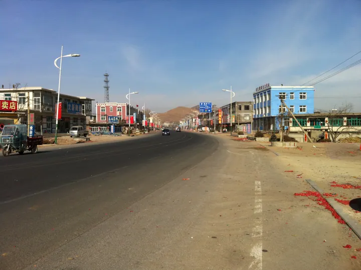 A town street with colourful buildings and a mountain backdrop in Wafangdian