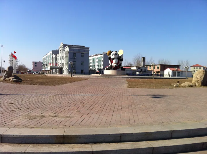 Open plaza with a large panda statue and government building in Dashiqiao