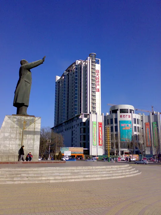 Modern high-rise building and a statue in a plaza, Haizhou District, Fuxin