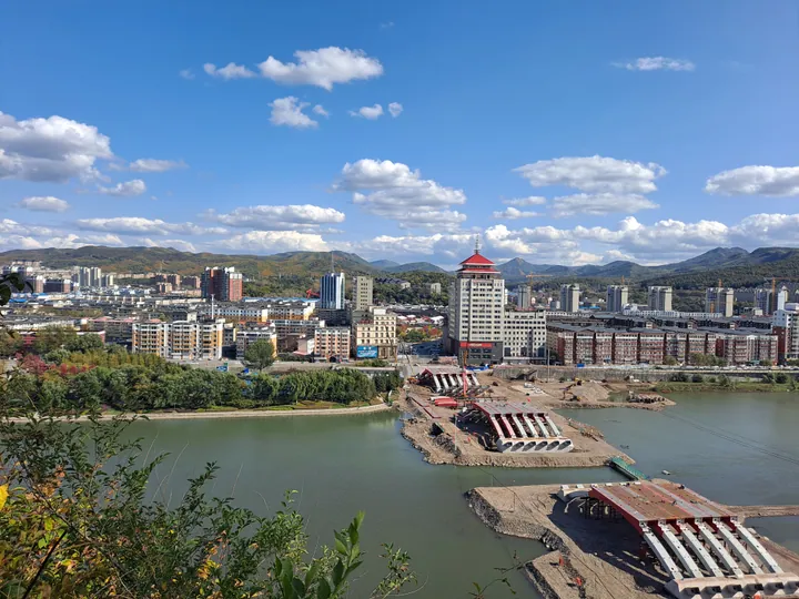 A river winding through a city skyline seen from a hillside park in Tonghua, China