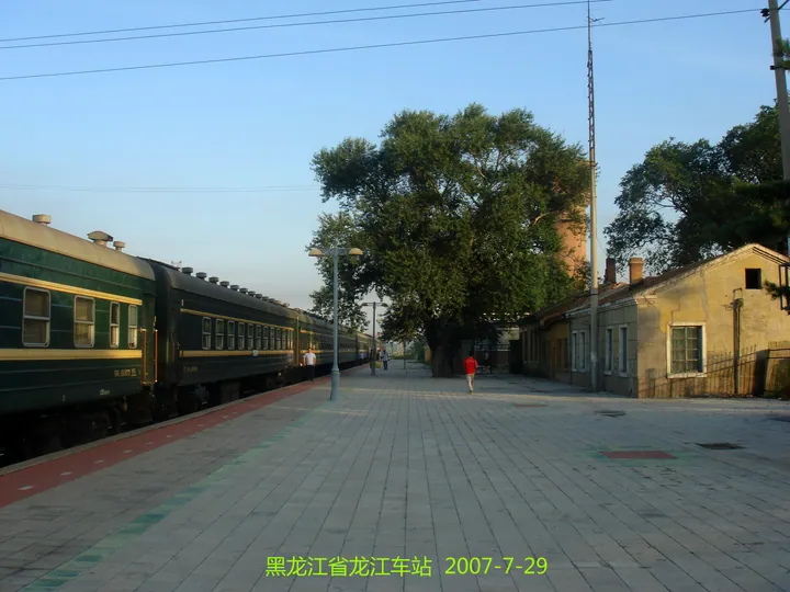 Old green passenger train at Longjiang Railway Station platform