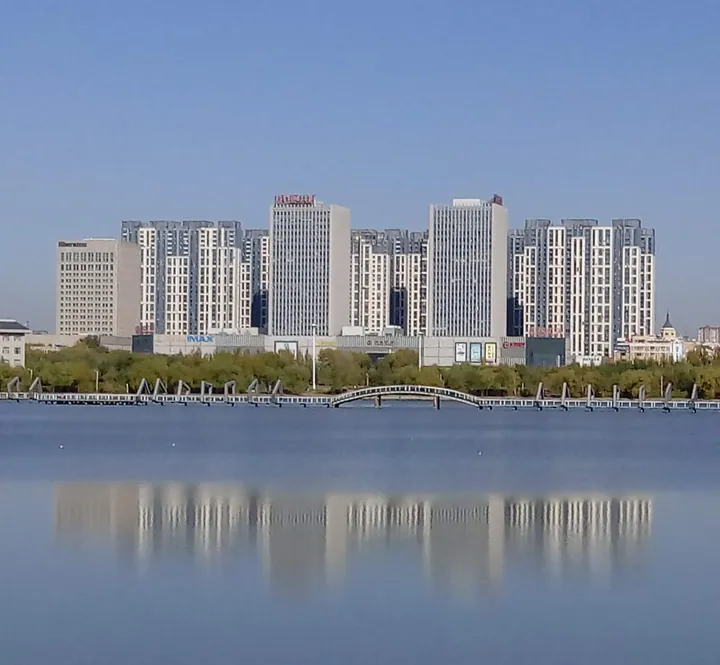 High-rise skyline reflected in Wanbao Lake in Sartu District, Daqing