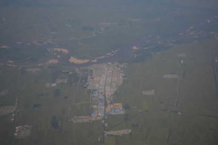 Hazy aerial view of Huachuan County's town centre next to the Songhua River