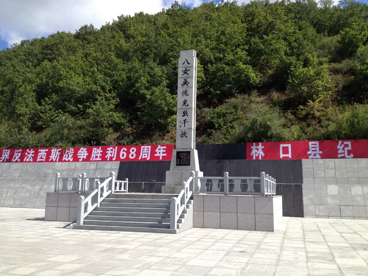 A stone memorial obelisk with red banners commemorating the Eight Heroines in Linkou County