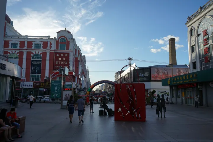 A lively pedestrian shopping street with colourful European-style facades under a blue sky