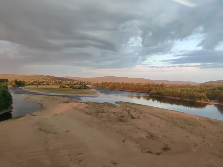 River landscape with forested hills at dusk in Tahe County