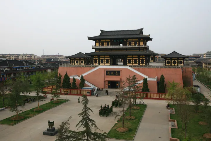A traditional Chinese pavilion building atop a red terrace with a courtyard in front