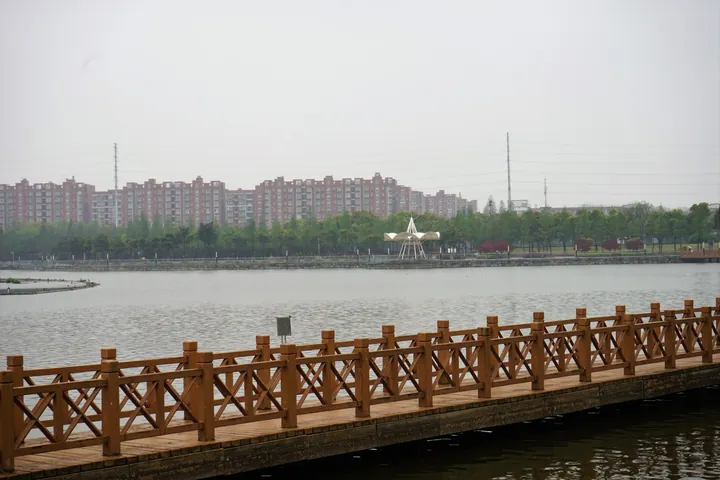 A wooden pier on a lake with apartment towers in the background in Jintan, China