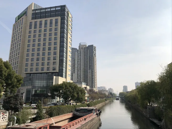 River canal with barges, willow trees and riverside buildings in Taicang