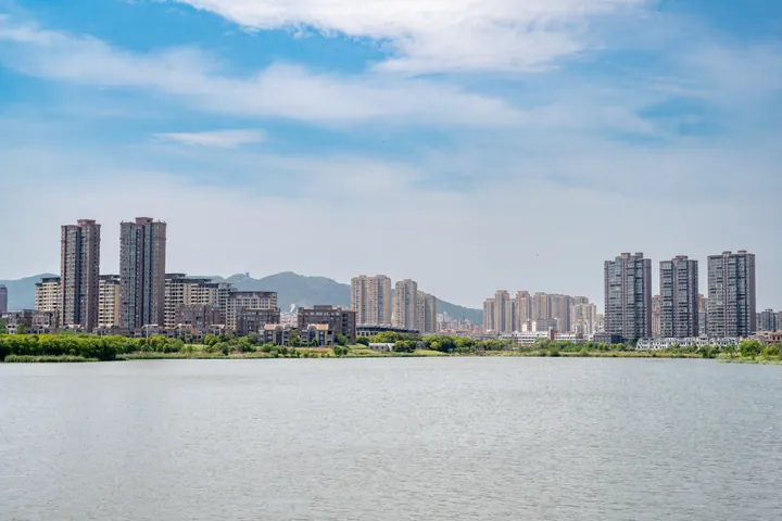 A lake in front of high-rise apartment towers under a blue sky in Dantu District, Zhenjiang