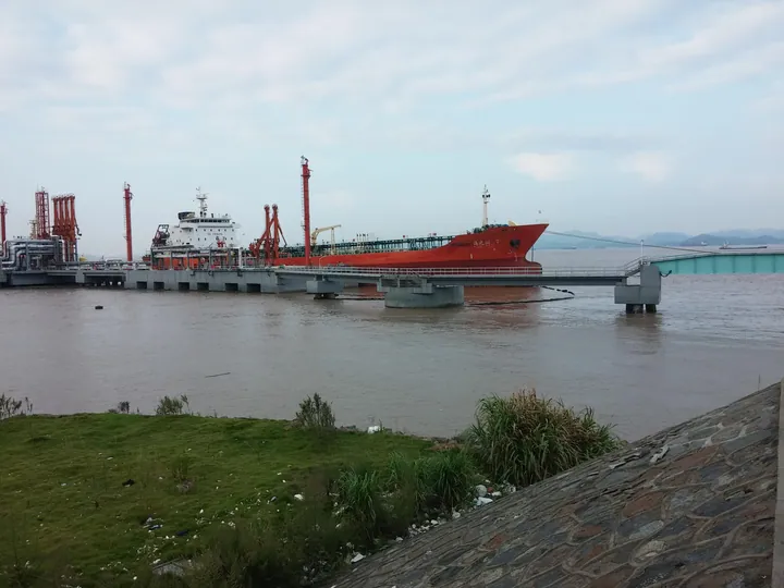 Red-hulled tanker ship at an industrial dock in Beilun District
