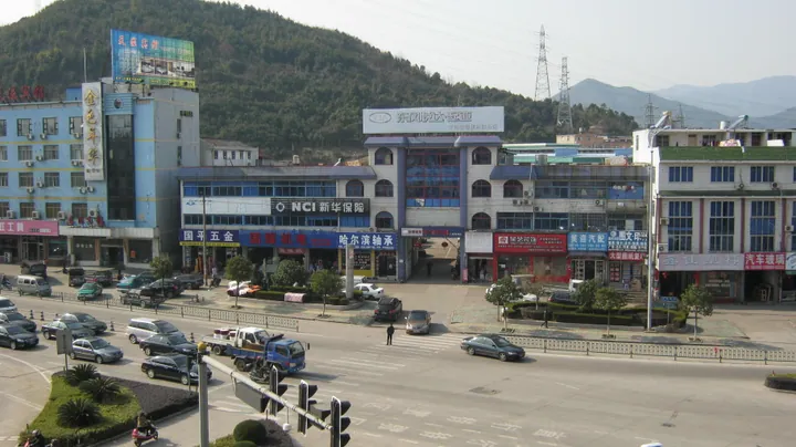 A street junction with shops and a wooded mountain rising behind in Ninghai County