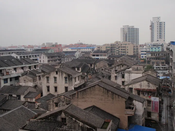 Traditional tiled rooftops with modern towers in the background in Pingyang County