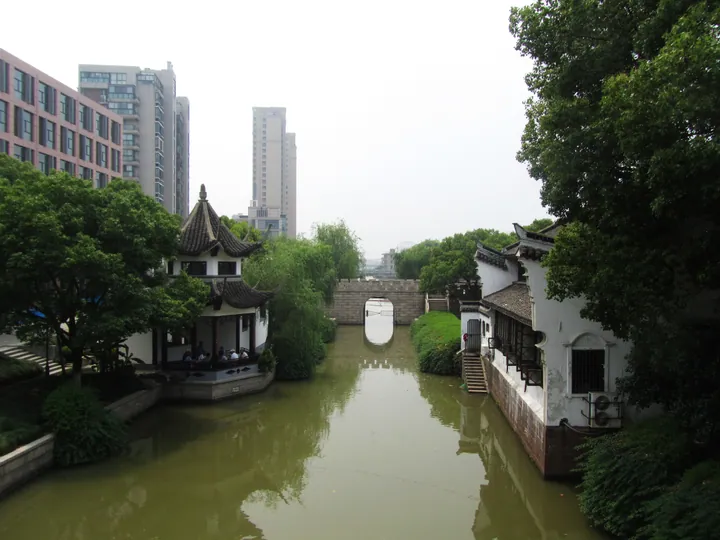An arched stone water gate spanning a canal lined with traditional buildings