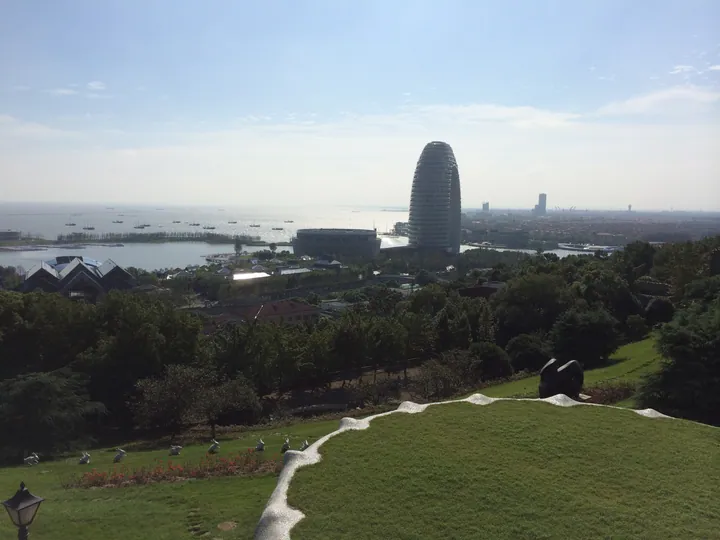 Hilltop garden overlooking a lake with a modern tower and skyline in Changxing County