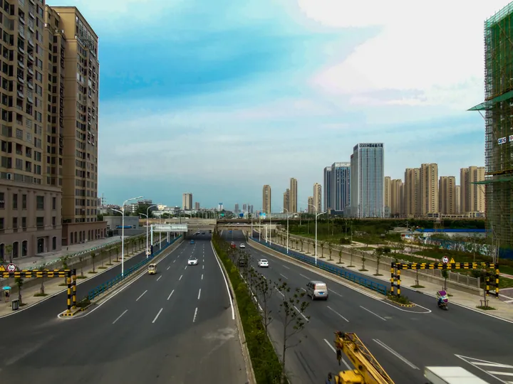 An elevated avenue running toward high-rise towers, alongside a railway line