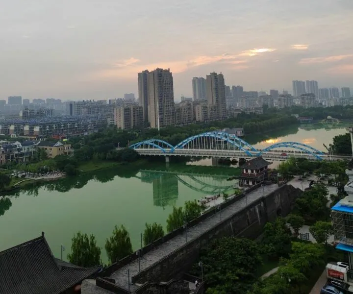 A river with an arched bridge and city buildings lit by sunset