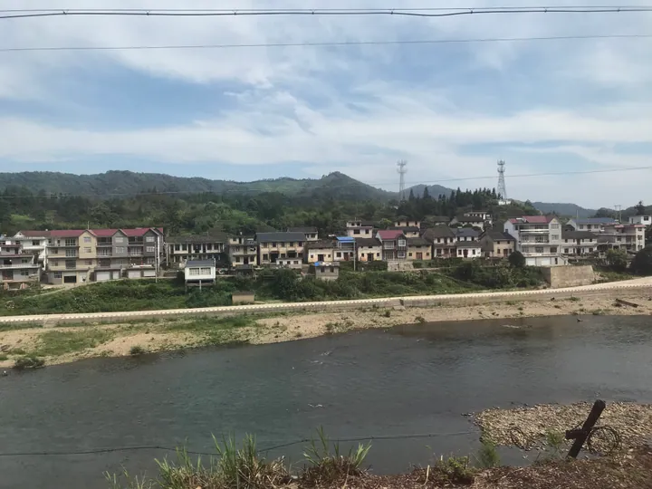 Riverside village houses with wooded hills behind in Qimen County