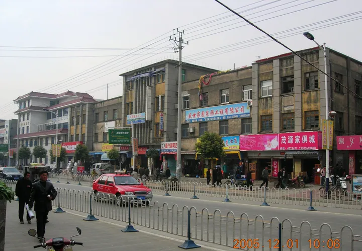 A city street lined with multi-storey buildings and shopfronts in Dingyuan County