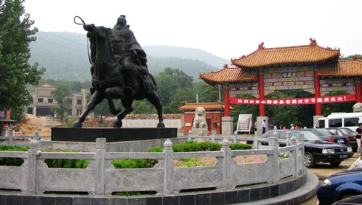 Bronze equestrian statue and ornate red gate at a scenic area entrance in Xiao County