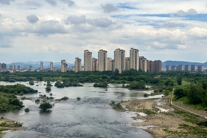 High-rise apartment towers along a wide river with wetland islands