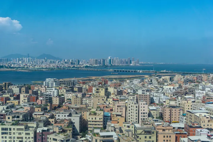 Aerial-level view of Haicang rooftops with Xiamen's skyline across the water