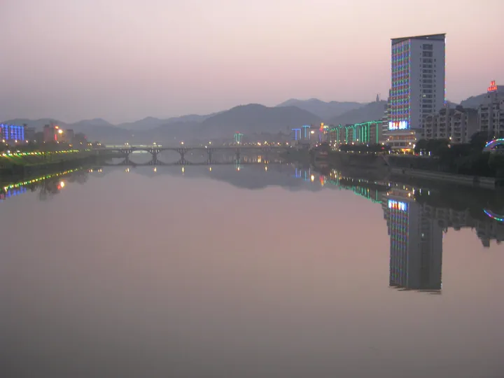 Twilight riverside skyline of Shaxian District with a reflected bridge and high-rise