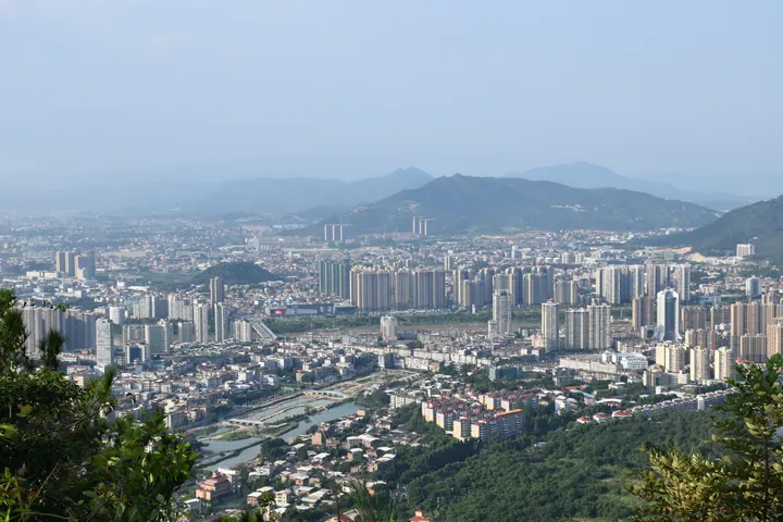 Wide panorama of Nan'an's downtown skyline along a river, with mountains in the background