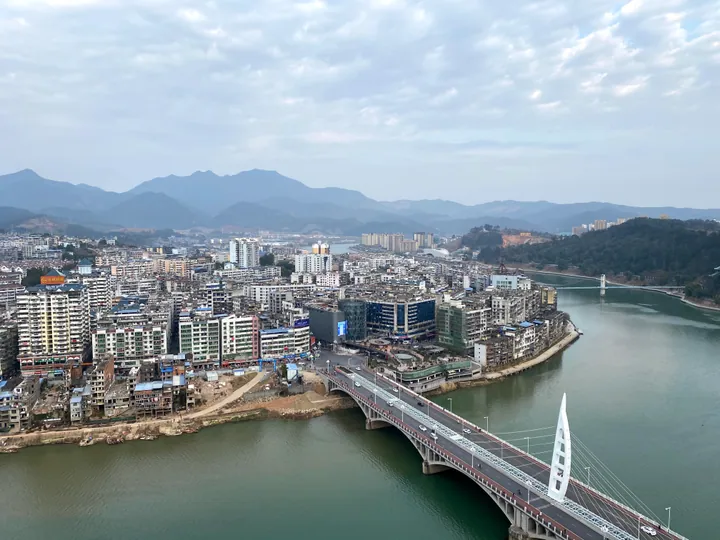 An aerial view of a riverside town surrounded by hills in Fujian, China