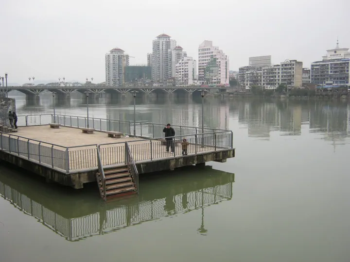 A riverside viewing platform with Bayi Bridge and the skyline of Shaowu in the background