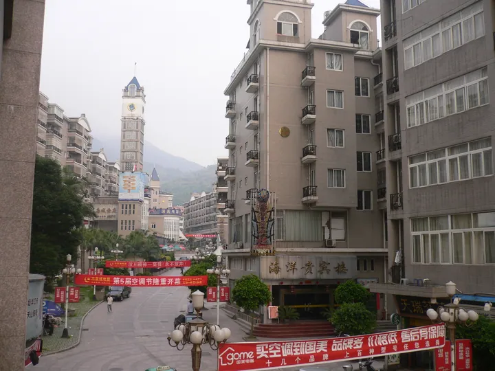 Town street with a clock tower and a hotel building, banners along the roadside
