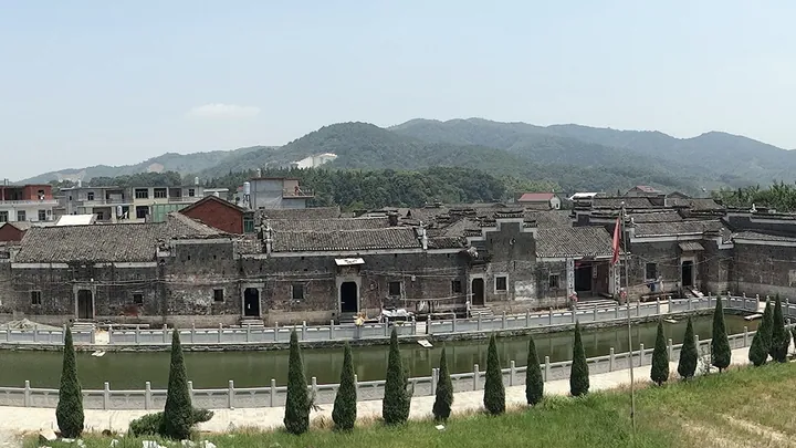 Historic walled Gan-style building complex surrounded by a moat and forested hills