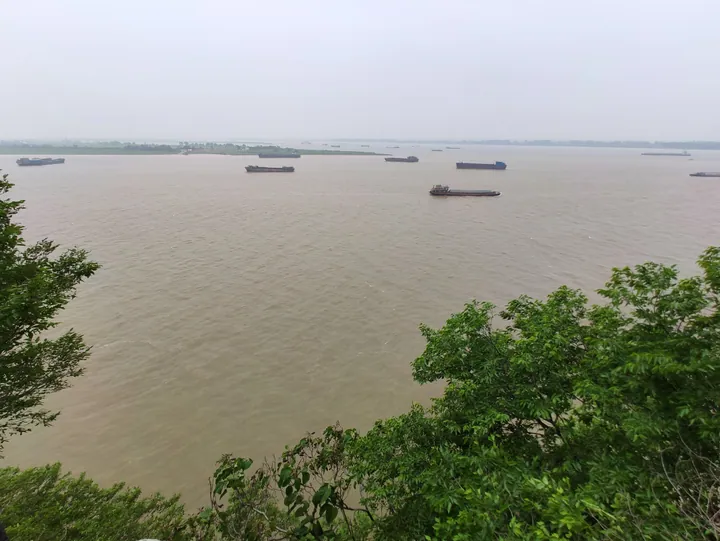 Cargo barges on a wide river seen from a hillside viewpoint in Hukou County
