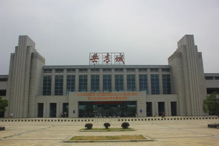A modern railway station building with red banners under a blue sky