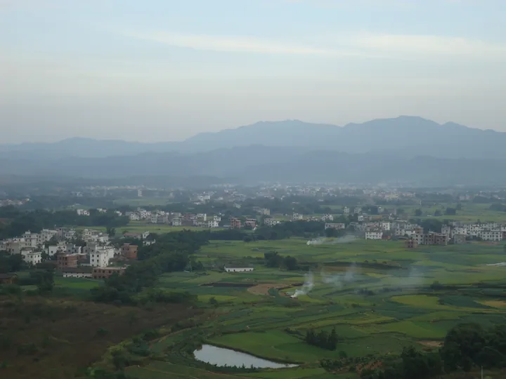 Farmland and villages in Xincheng town, Dayu County, with hills in the mist