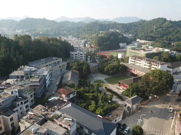 Aerial view of a hillside town with mixed older and newer buildings in Xunwu County