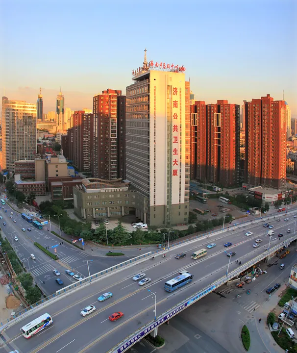 A golden-hour view of an elevated highway with traffic beneath tall red-brick apartment towers