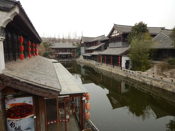 Traditional buildings with red lanterns reflected in a canal at Tai'erzhuang ancient town