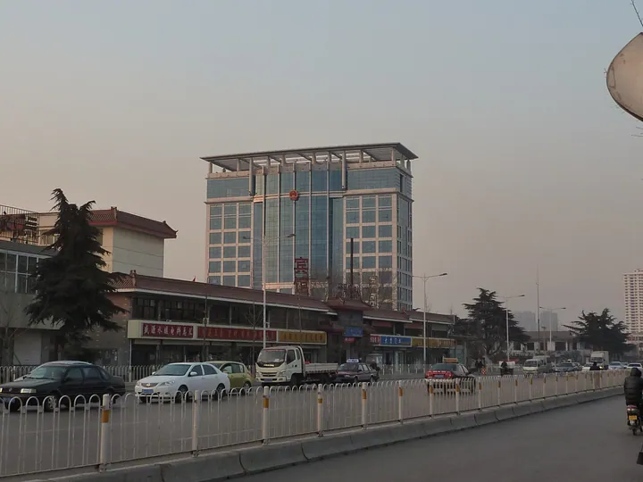 A city street at dusk with an illuminated tower building