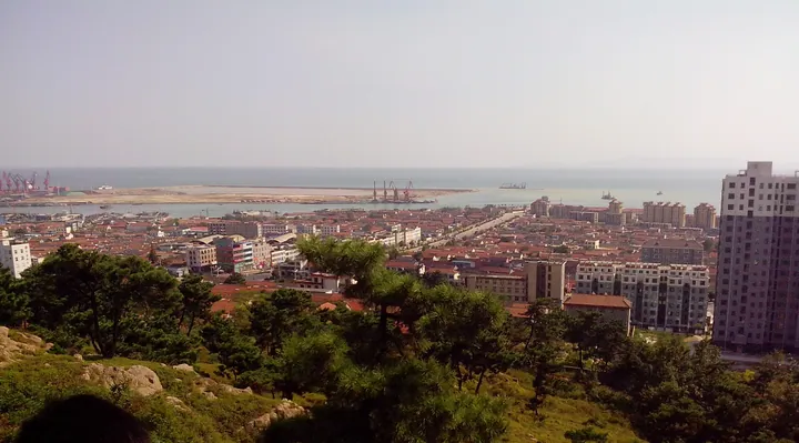Elevated view of the coastal port town of Lanshantou with cranes and sea in the background