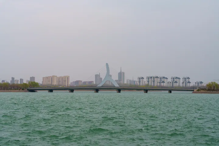 A bridge crossing a lake with city towers in the background
