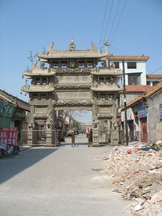 An ornately carved stone memorial arch spanning a street, Shan County