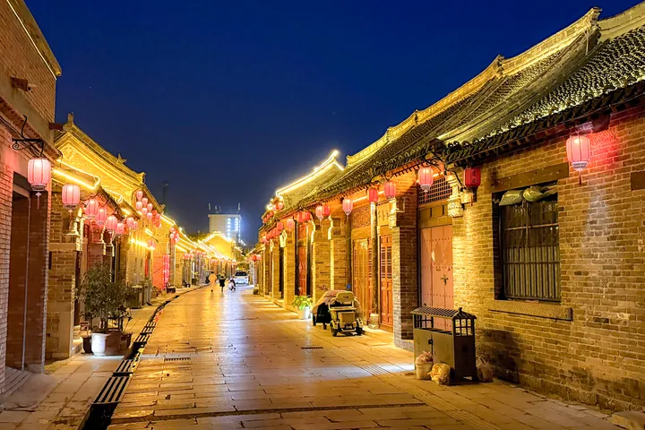 A lantern-lit traditional brick street at night in Daokou, Hua County