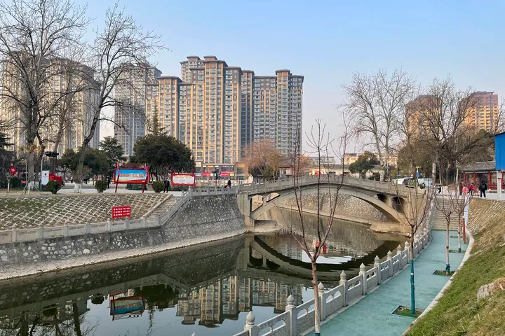 Park bridge over a canal with high-rise buildings behind