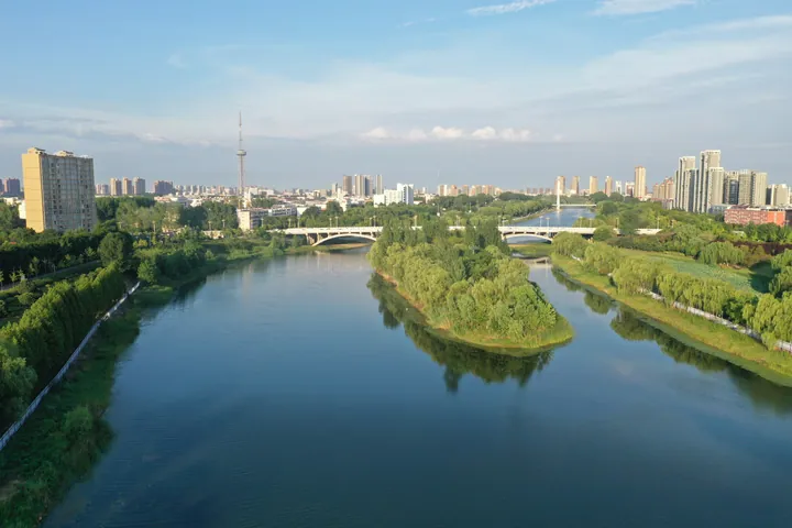Drone view of a river winding through a city at golden hour