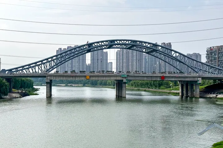 Arch bridge over a river with high-rise towers behind