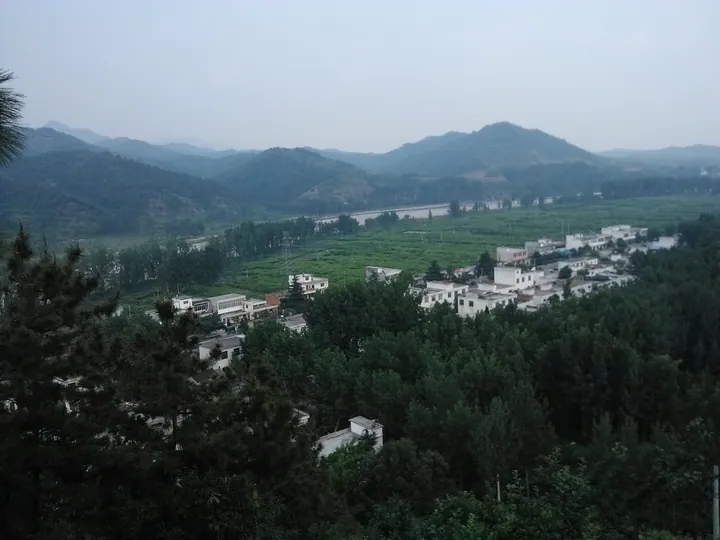 A village nestled among green hills in Neixiang County, Henan