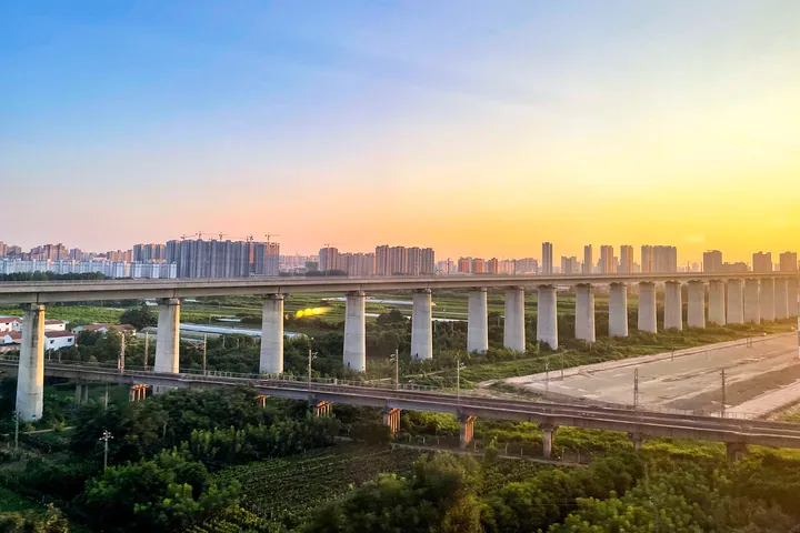City skyline at sunset behind a railway viaduct in Shangqiu, Liangyuan District