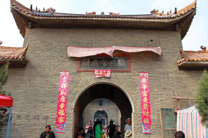 Ornate temple gate with red festival banners in Luyi County